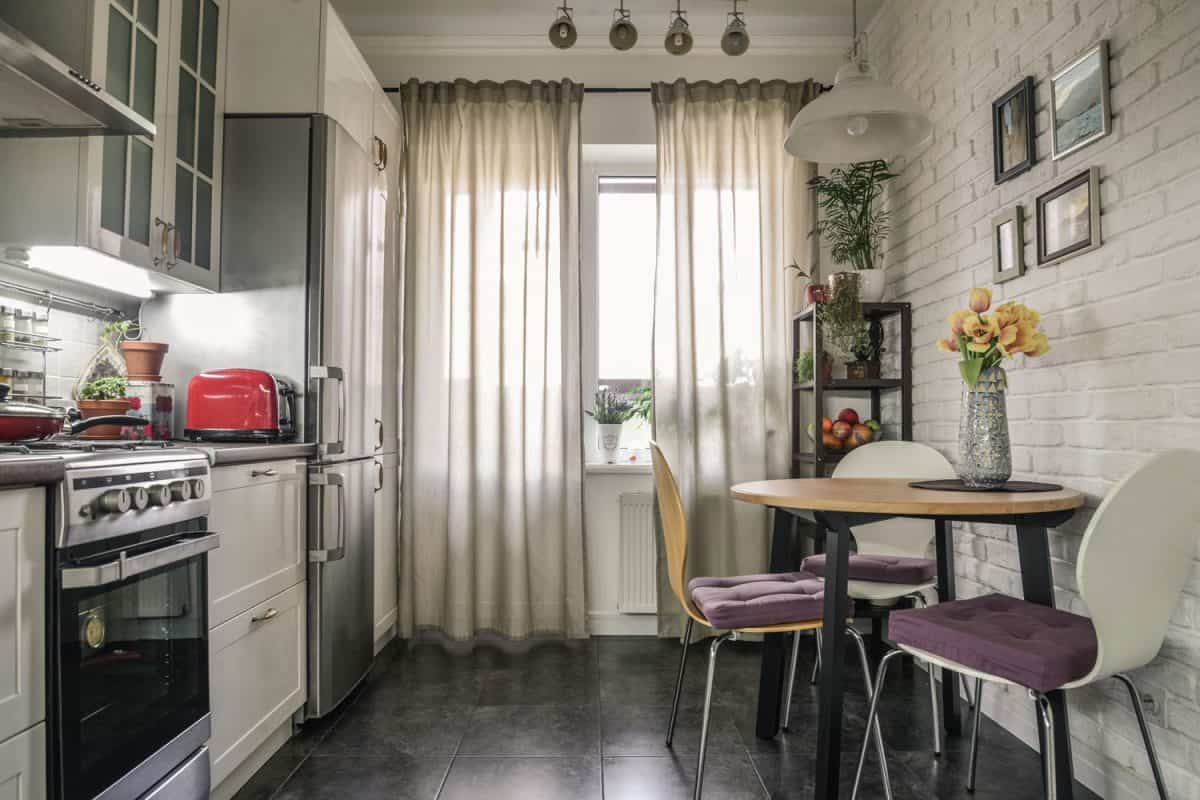 A narrow apartment kitchen area with dark gray tile flooring