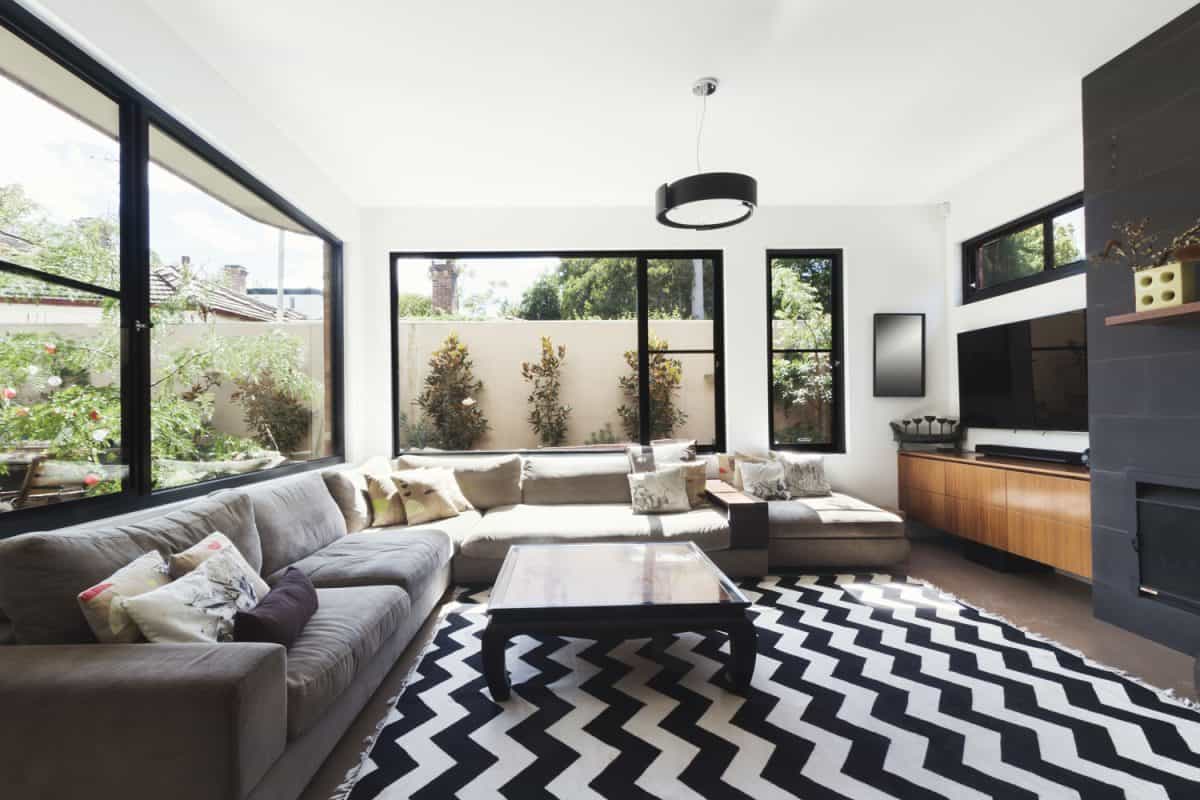 Black and white patterned carpet with white walls, black sectional sofa and white painted wall