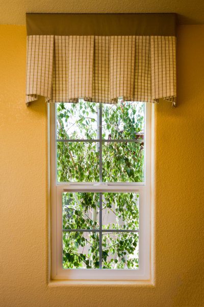 Small window in a house looking at a tree.