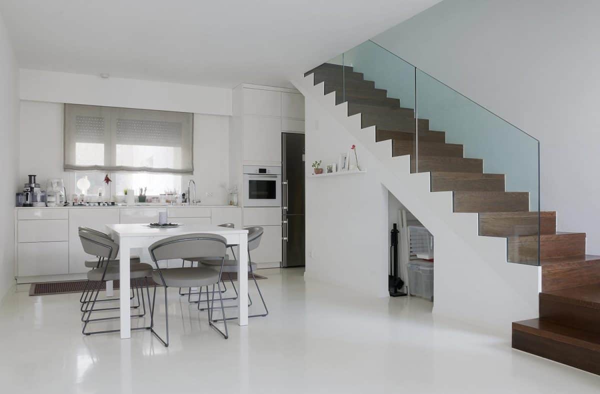 White kitchen and dining room with white epoxy floor and wooden stairs