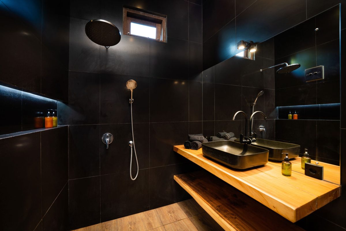 A black rustic designed bathroom with laminated flooring, a wooden countertop vanity and a huge mirror