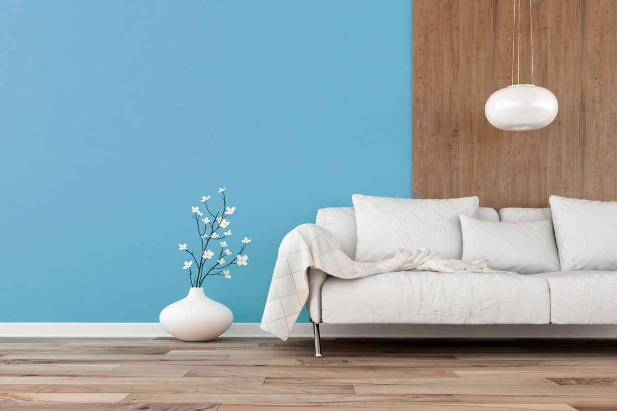 A blue accent wall matched with a wooden texture wallpaper and a white sofa
