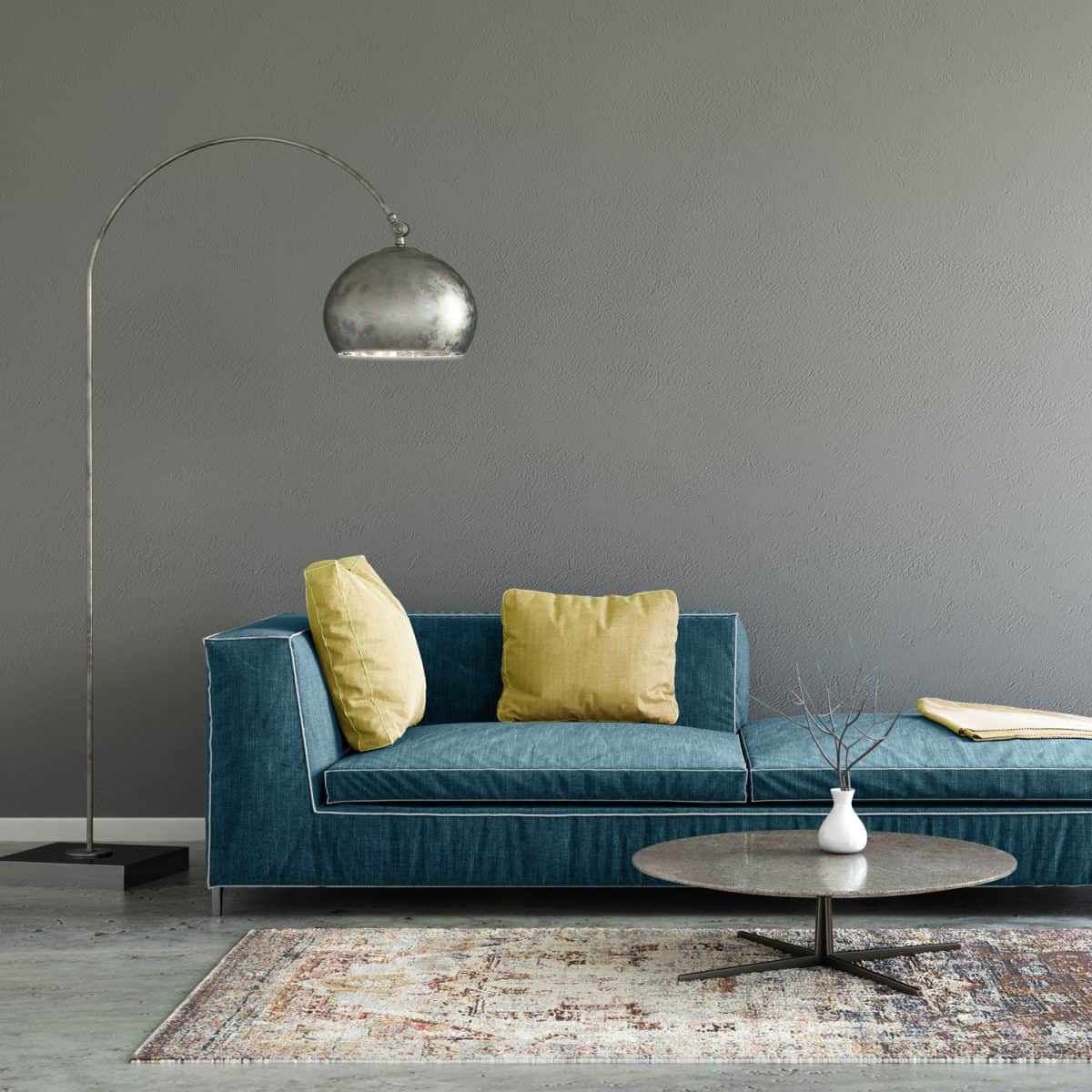 A blue sectional sofa with yellow throw pillows inside a gray living room