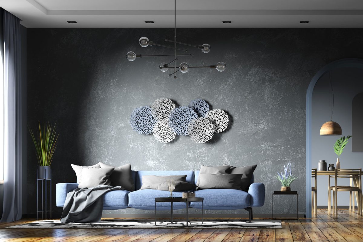 A blue sofa inside a black cement texture living room with wooden flooring and wall decors on the wall