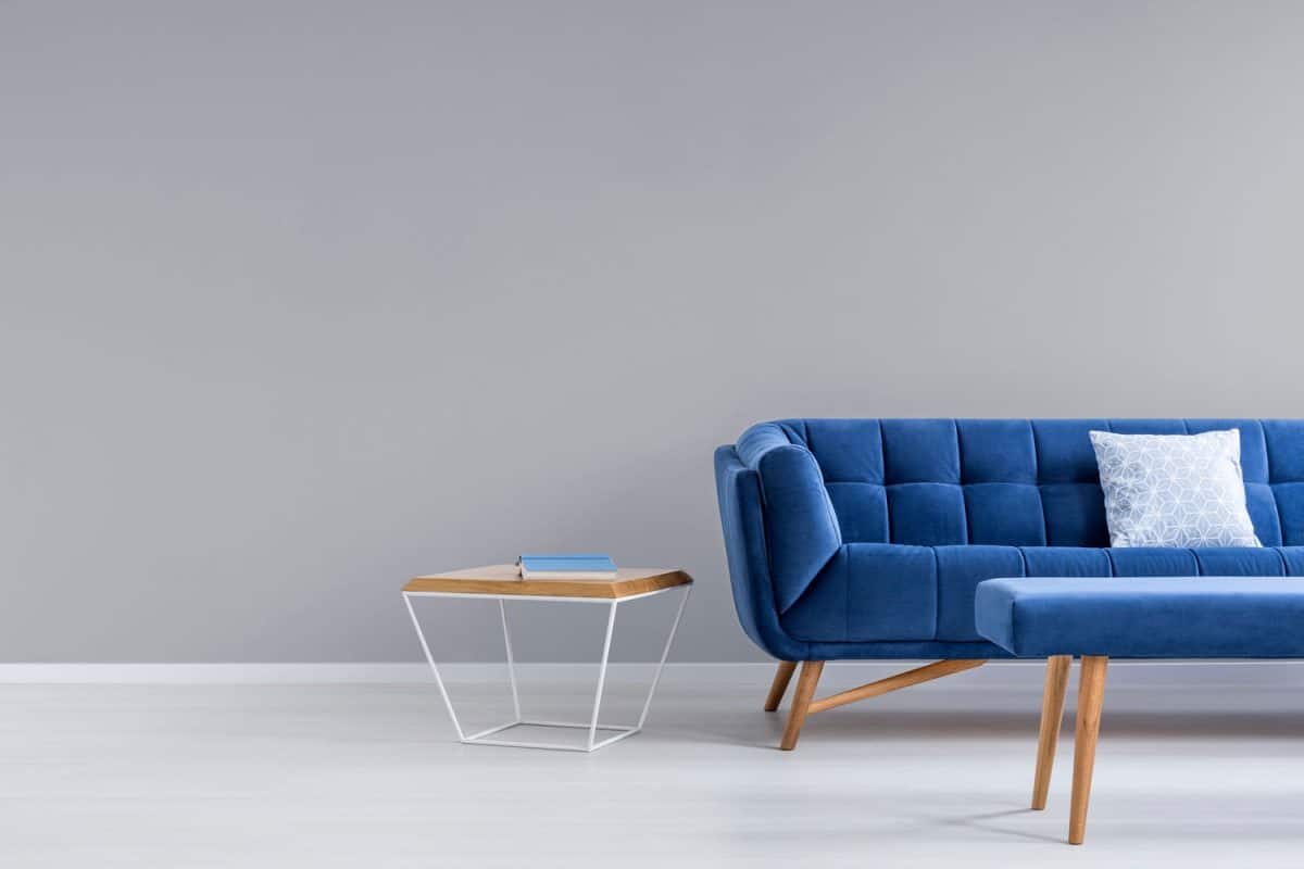A blue sofa with a blue upholstered ottoman in the living room with gray walls