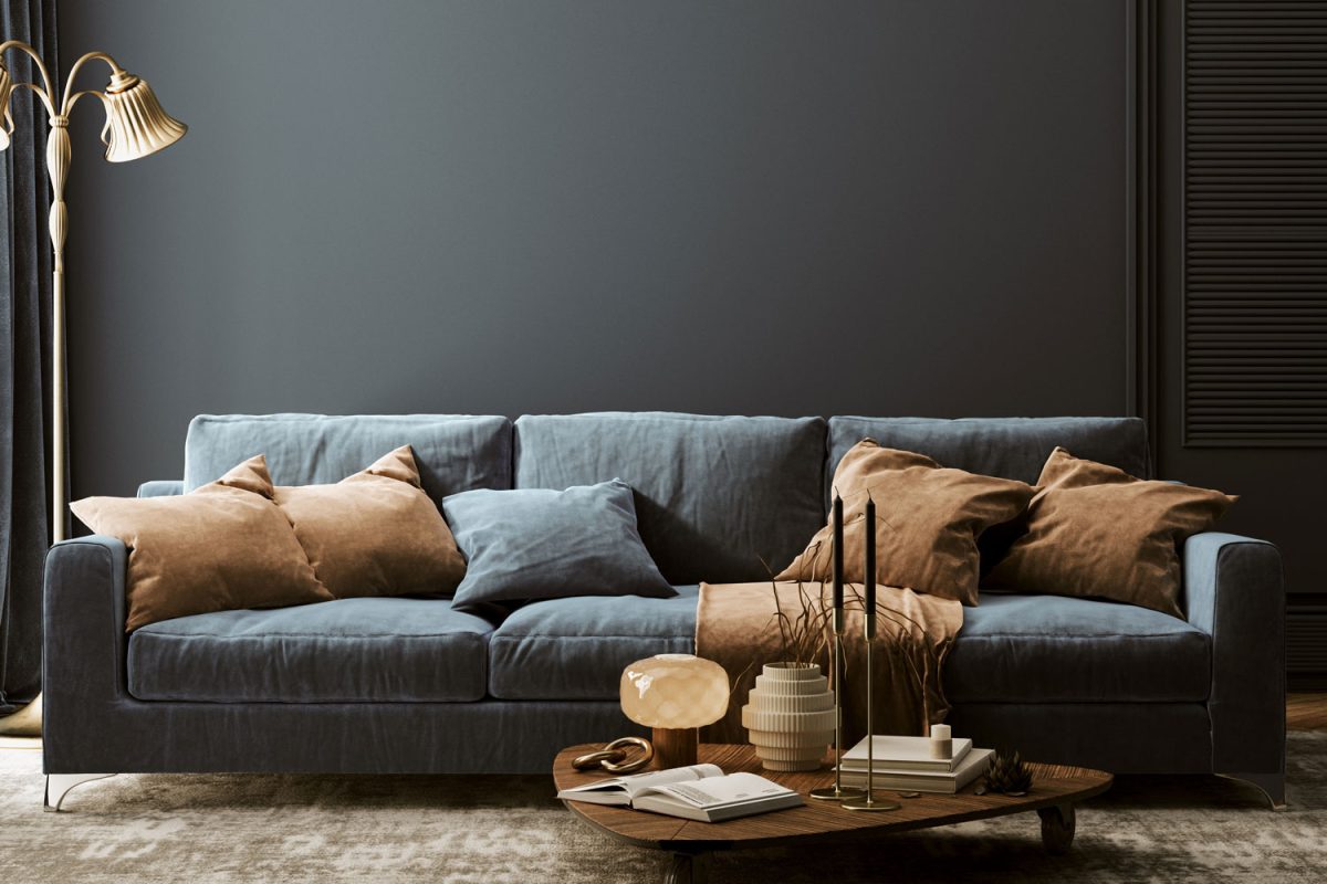 A blue sofa with brown throw pillows inside a dark blue colored living room