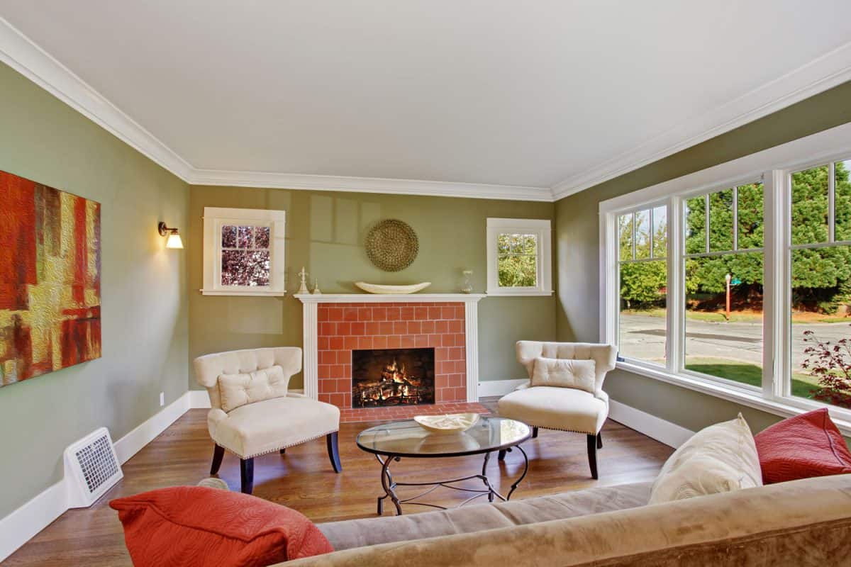 A bright light green colored wall with white trims on the ceiling with a brick fireplace