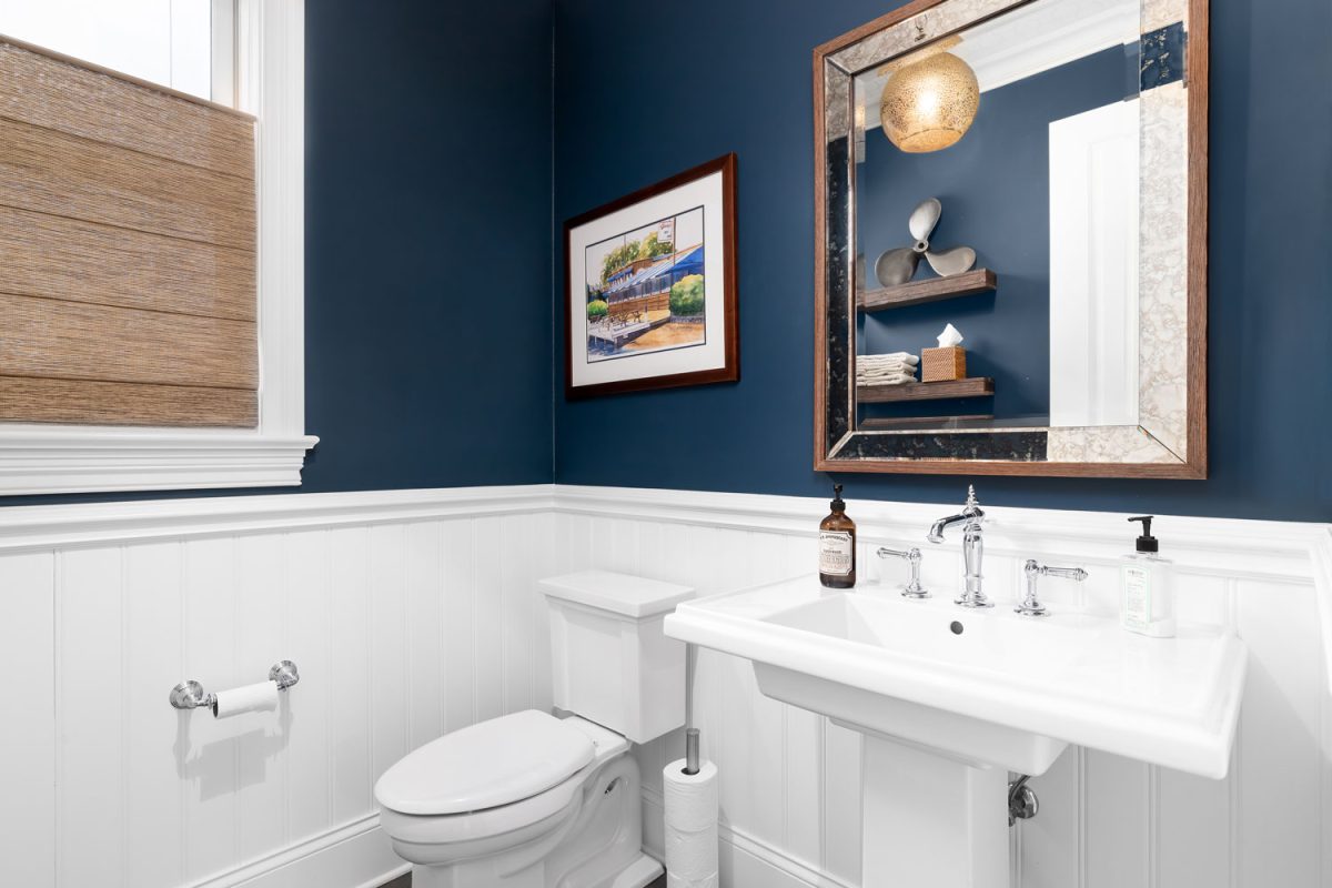 A dark blue painted bathroom with a white base matching the fixtures and paneling