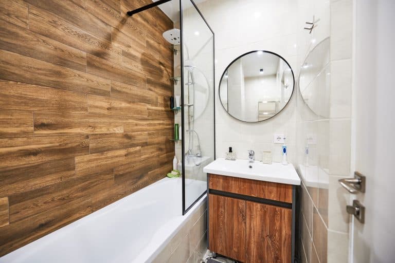 A gorgeous modern bathroom with a wooden decorative wall and white tiled walls, 9 Ideas For Bathroom Walls That Don't Use Drywall
