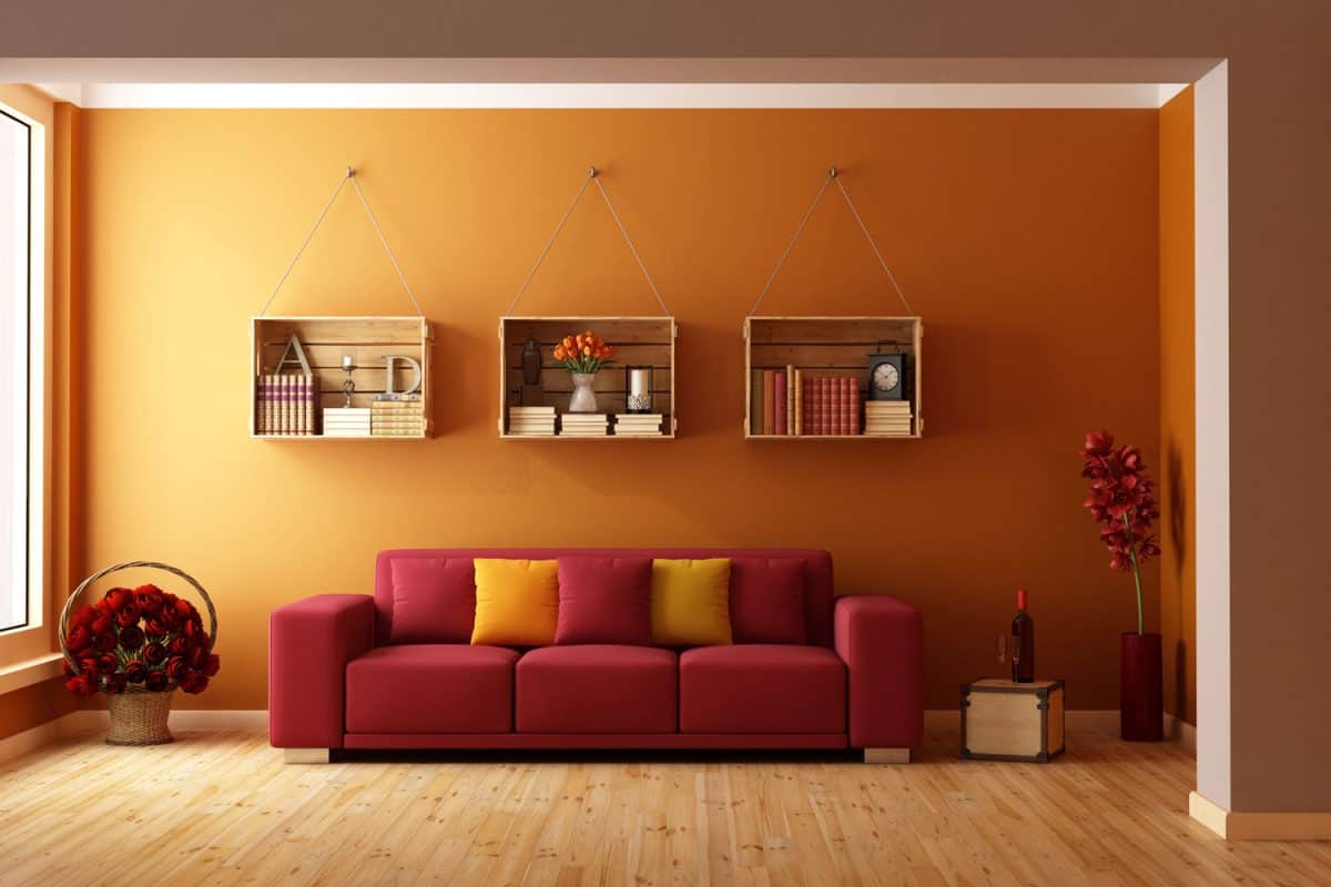 A gorgeous orange minimalist inspired living room with a red sofa and red throw pillows