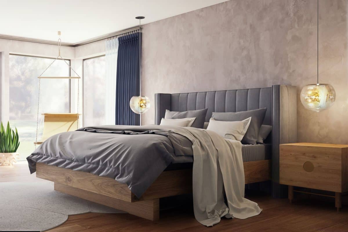 A gray bed with gray beddings and a wooden nightstand