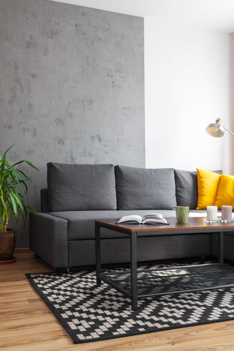 A gray modular sofa with gray throw pillows and a minimalist coffee table inside a wooden floored living area