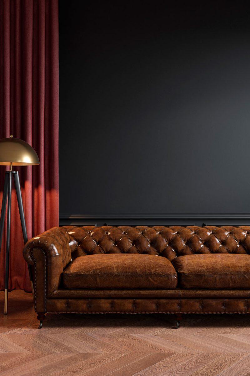 A long leather sofa with a golden lamp and a red ceiling high curtain