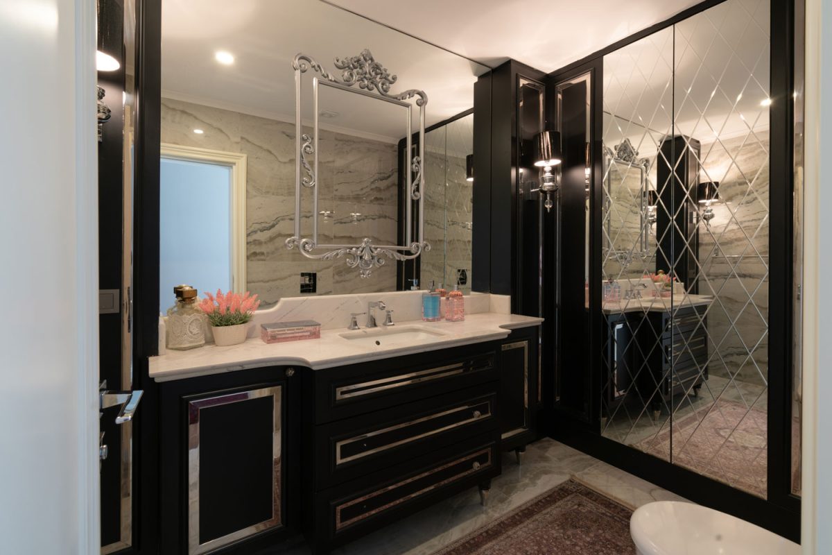 A luxurious black and white designed bathroom with huge mirrors running throughout the bathroom