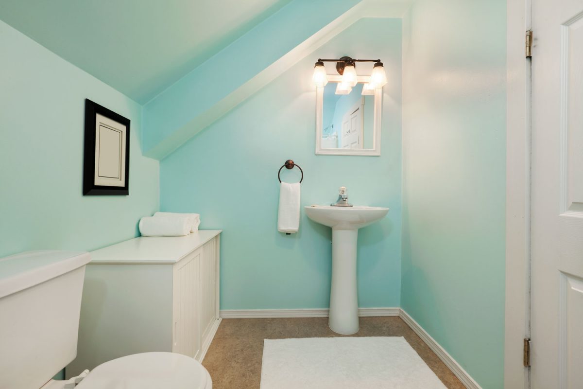 A mansard bathroom painted in light blue colored and white cabinets and fixtures