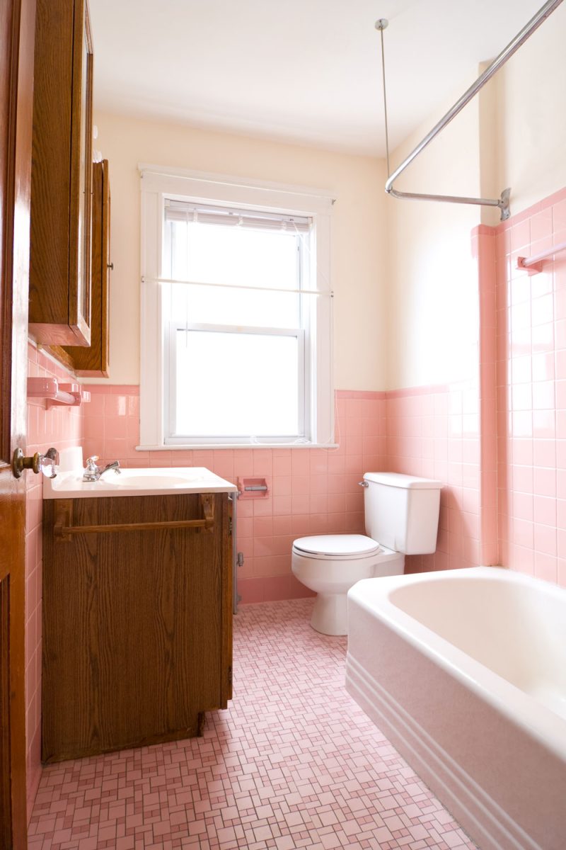 A pink and beige color combination bathroom with wooden vanity