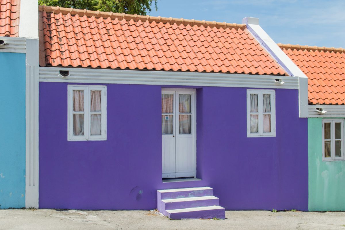 A purple colored house with white doors and window matched with red clay tile roofing