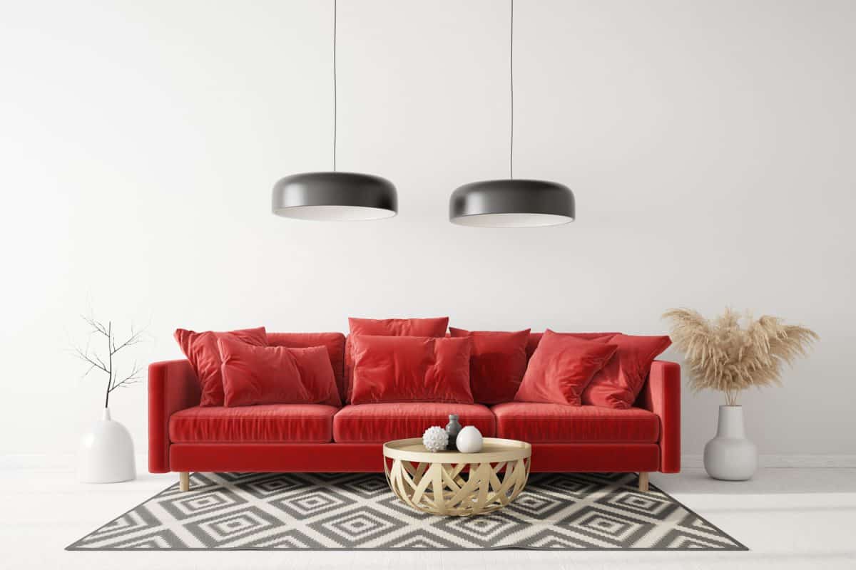 A red colored sofa with a wicker coffee table and dangling lamps