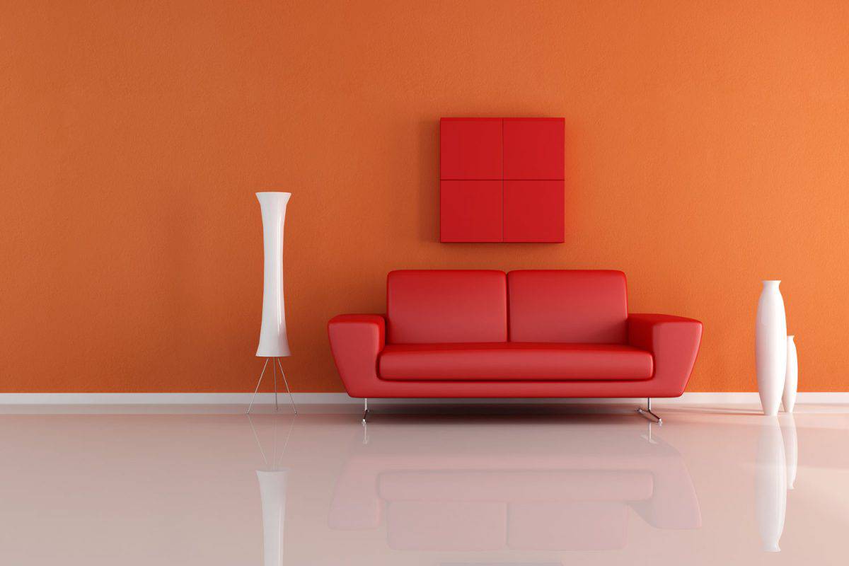 A red colored sofa with white modern vases and an orange wall