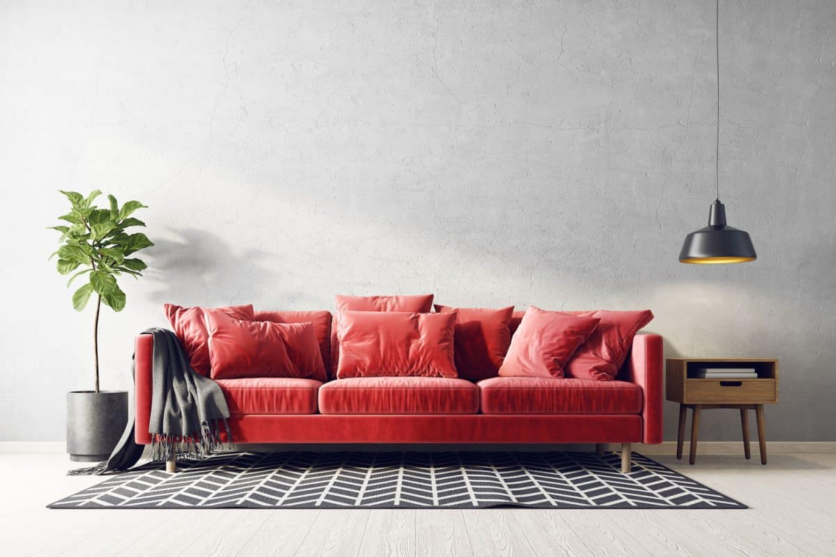 A red leather sofa with red throw pillows and indoor plants