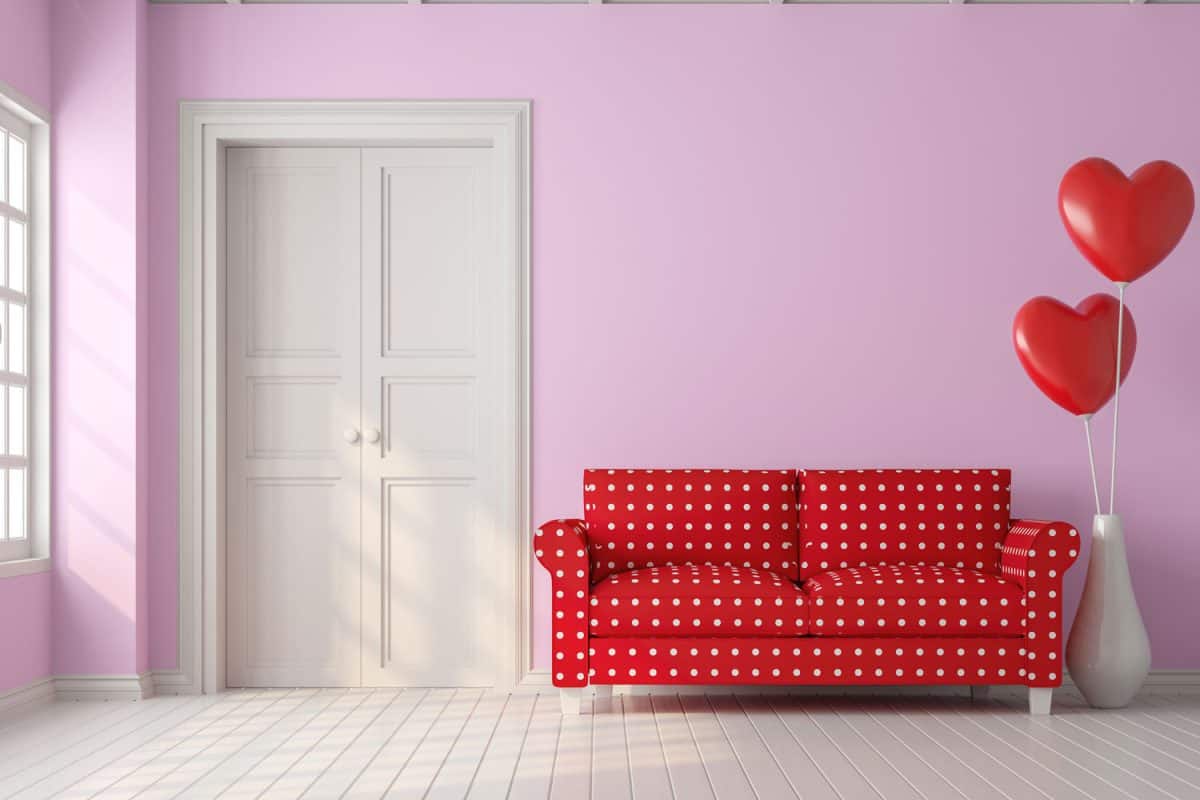 A red polka dot sofa with pink walls and balloons