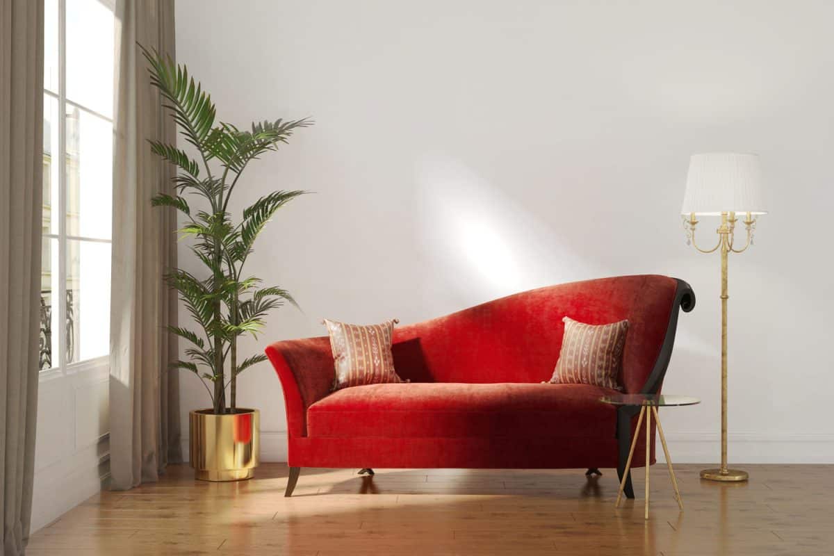 A red sofa with patterned throw pillows and indoor plants