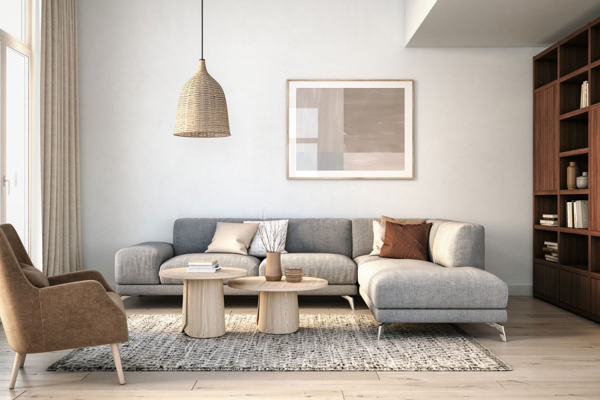 A sectional sofa with throw pillows inside a bright modern living area with a wicker dangling lamp