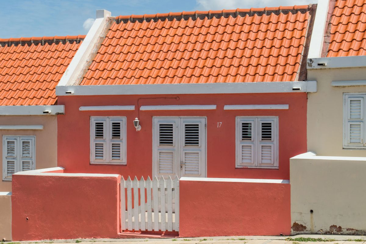 A small row house with red walls with white trims and door matched with clay tiled roofing