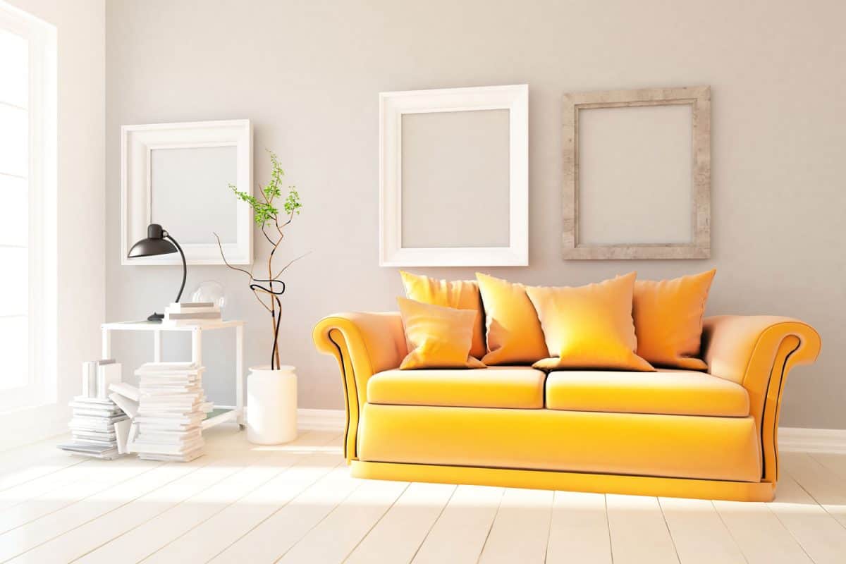 A yellow sofa with yellow throw pillows inside a white living room