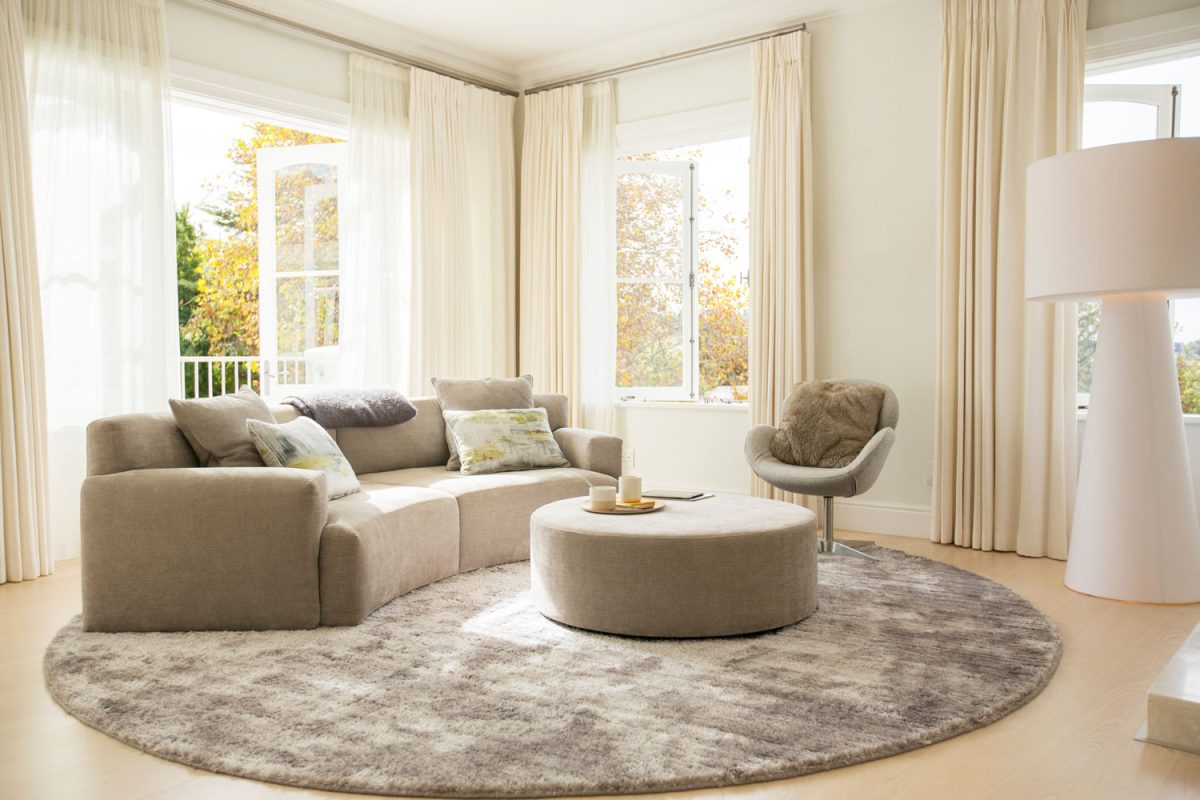 An oversized round rug inside a tan and bright living room