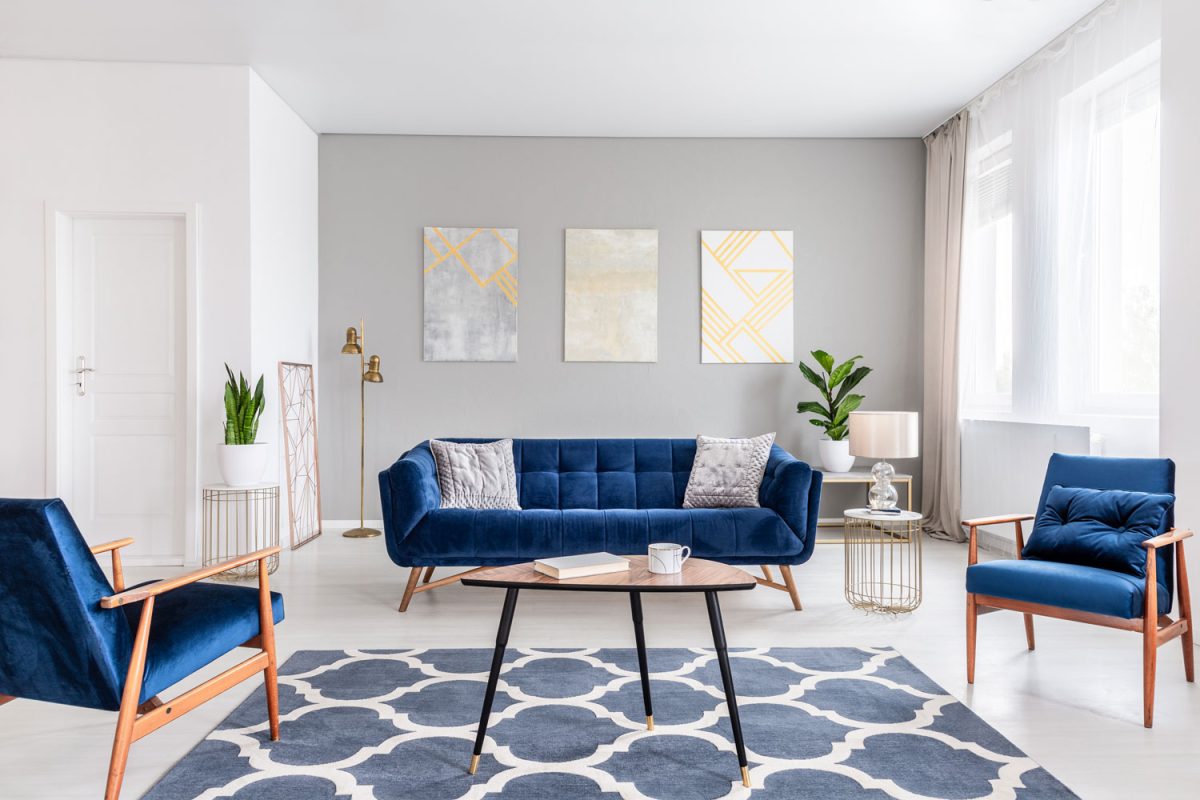 Blue armchairs and sofa inside a gray and white living room with a patterned carpet