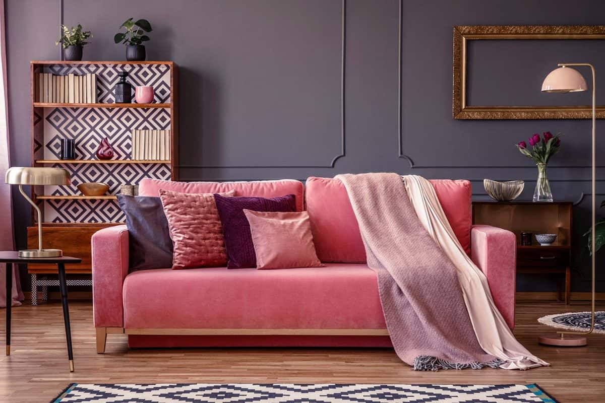 Front view of a pink sofa with pillows and blanket