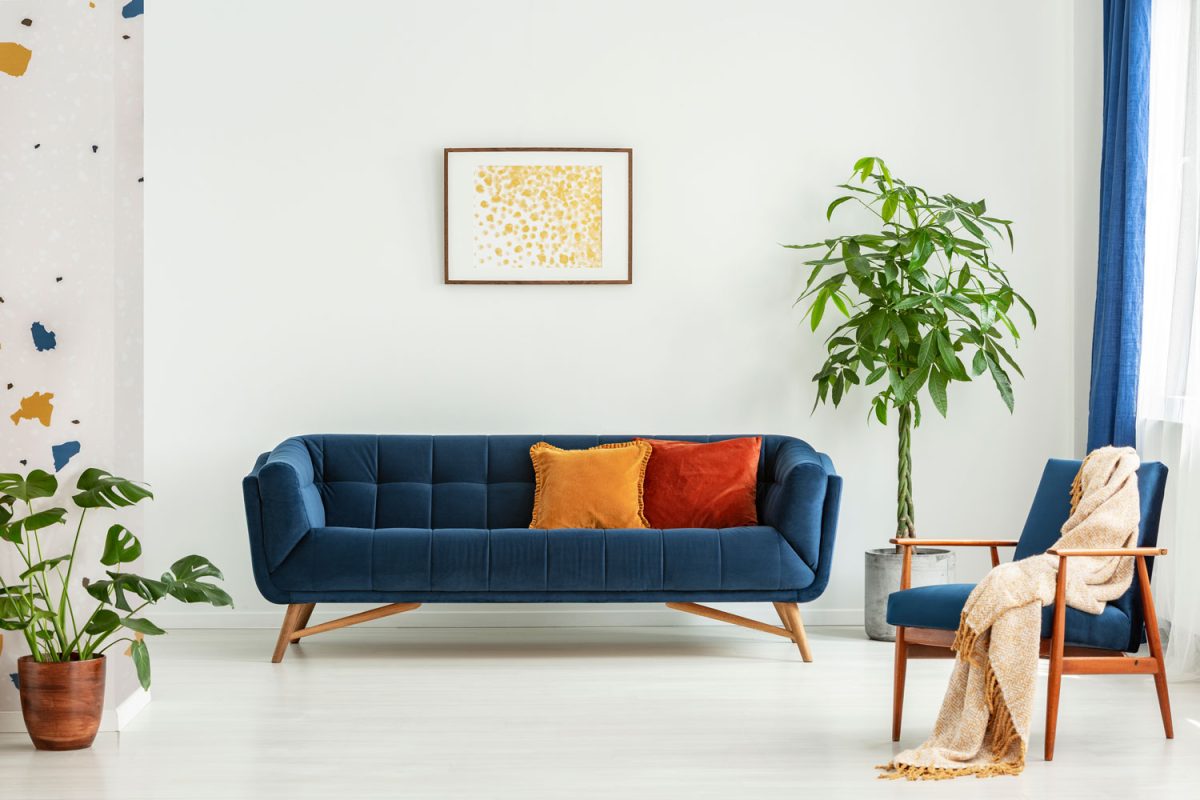 Interior of a bright living room with a blue couch and yellow and throw pillows
