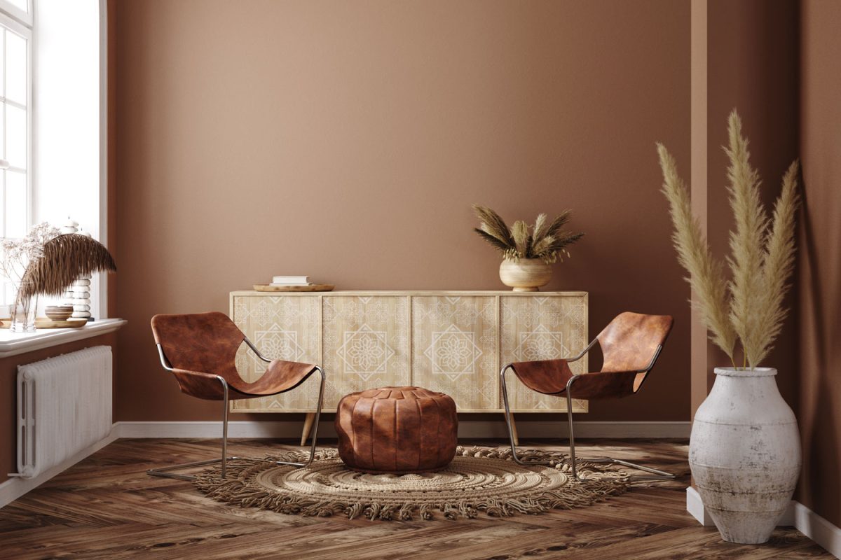 Interior of a modern living room with brown painted walls, brown leather arm chairs matched with and ottoman