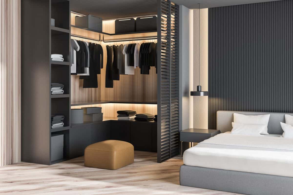 Luxurious modern bedroom with cloths hanged on the walk-in closet and a small nightstand on the side