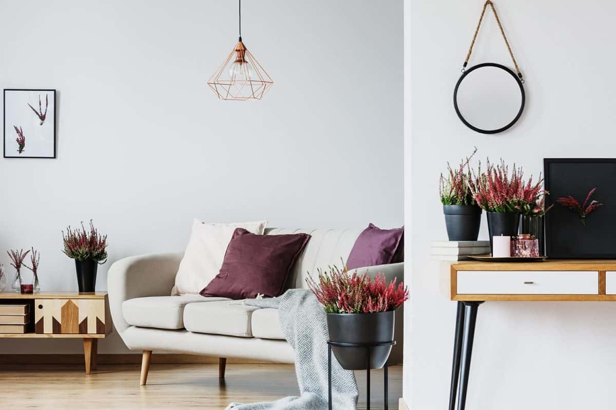 Mockup of round plate on wall above desk with heathers in cozy living room with copper lamp above sofa with purple pillow