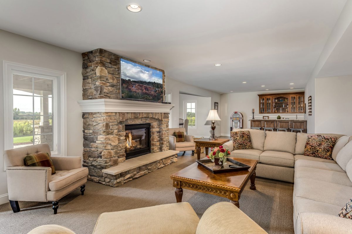 Rustic inspired living room with beige colored sectional sofas with a fireplace decorated with stone cladding