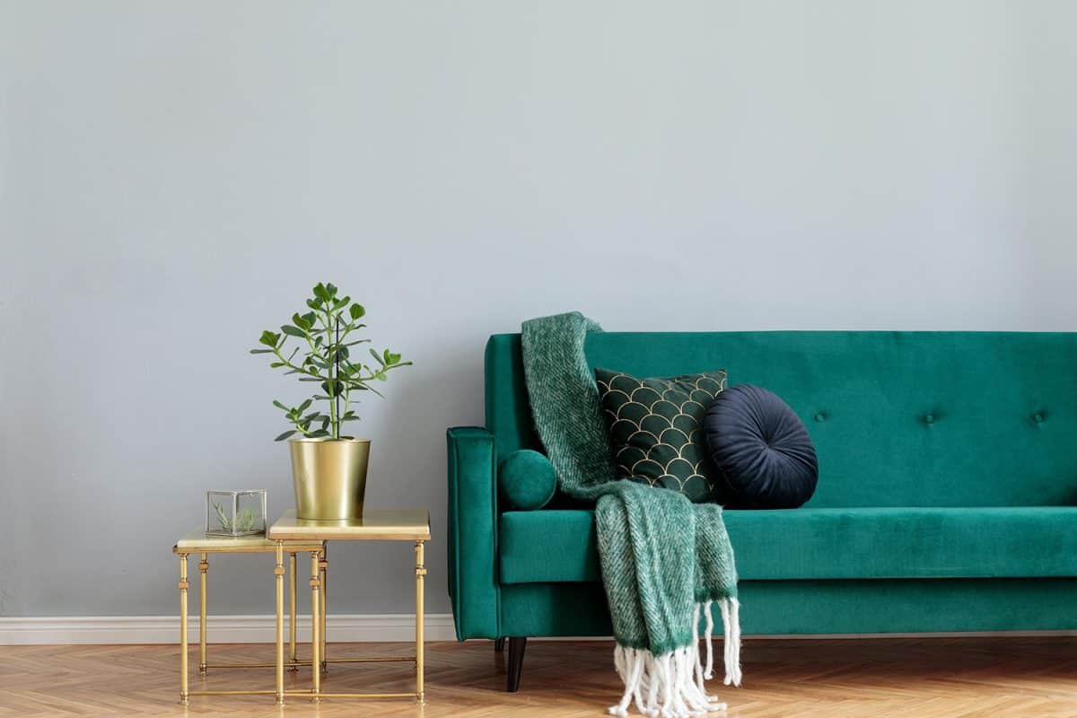 Stylish home interior with green velvet design sofa, gold coffee table