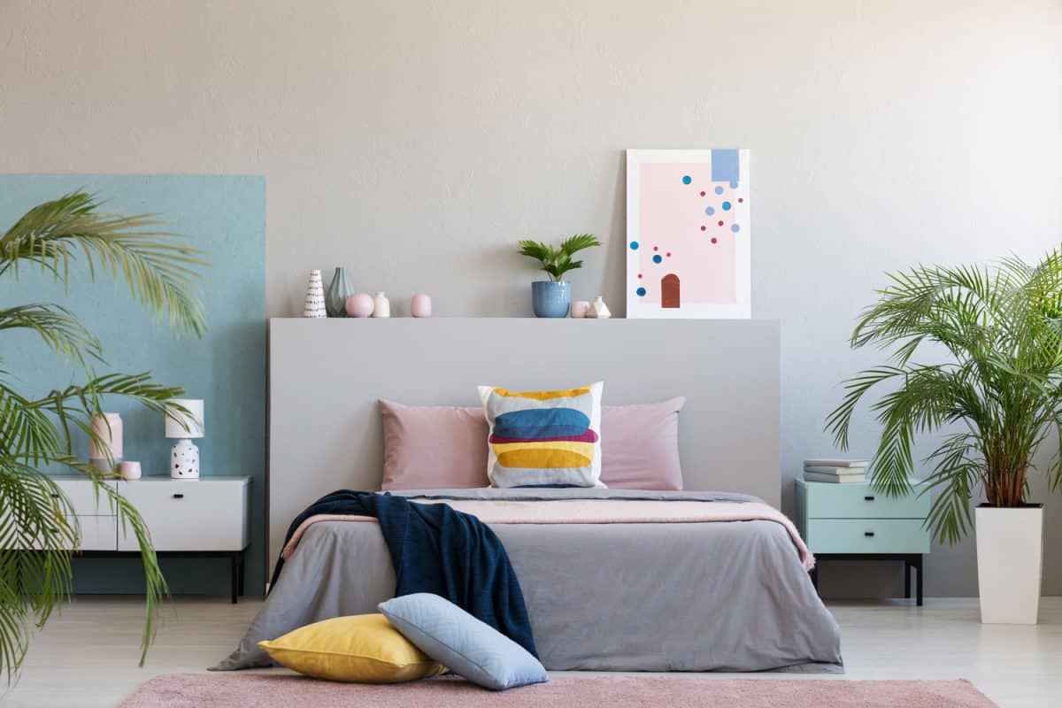 Stylish pink and other bright colored bedroom with a light blue nightstand and plants for decoration