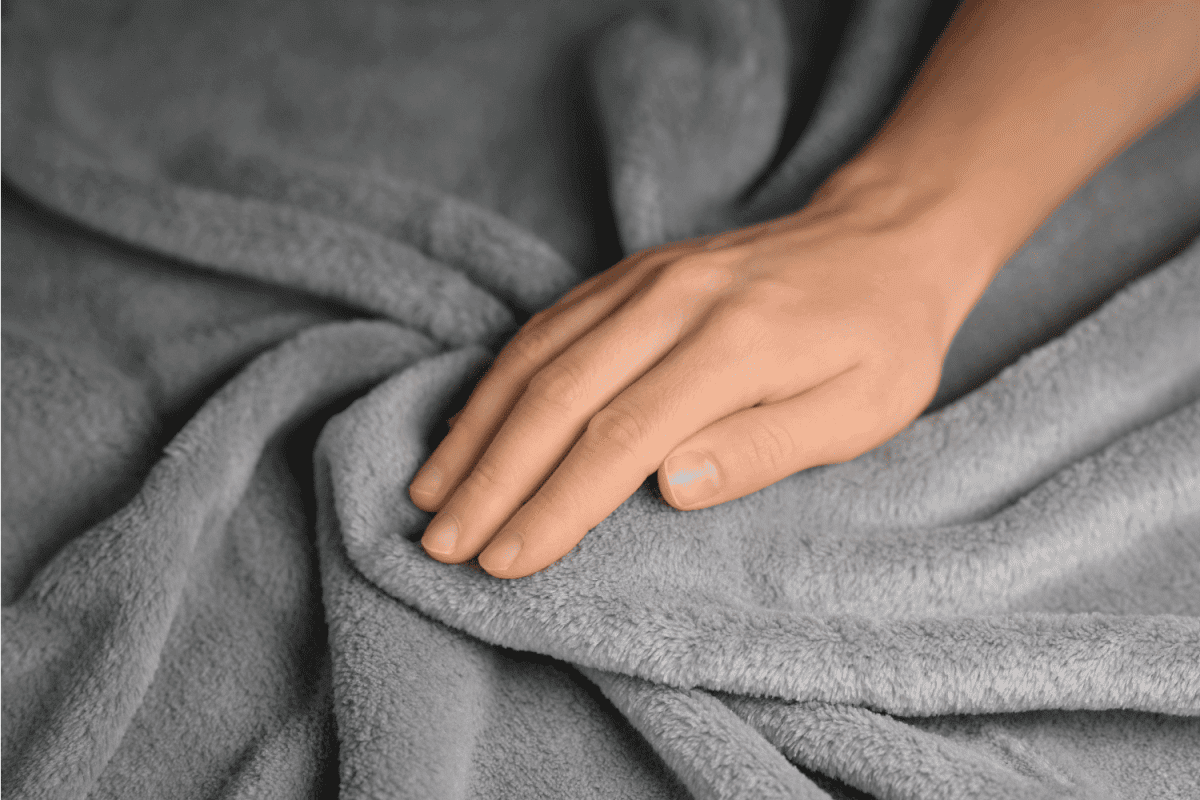 Woman touching grey blanket, close up. Close up of hand touching soft blanket.