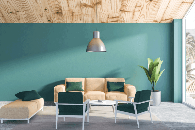 Interior of living room with green blue walls, concrete floor with beige couch and dark green armchairs and a neat coffee table. What Color Couch Goes With Green Walls
