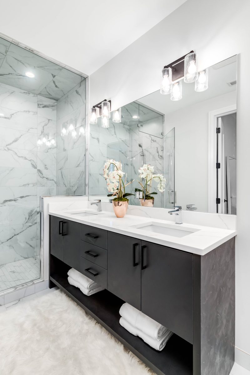 A beautiful, modern bathroom with a dark vanity and white granite counter top.
