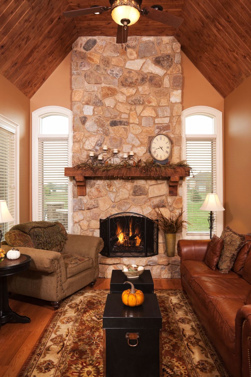 A brown leather sofa with a huge fireplace on the middle decorated with clocks