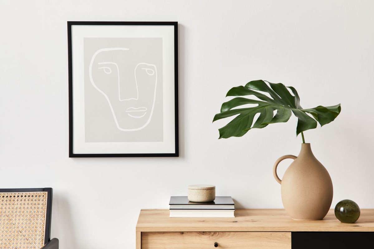 A canvas next to a wooden console table with a plant and books