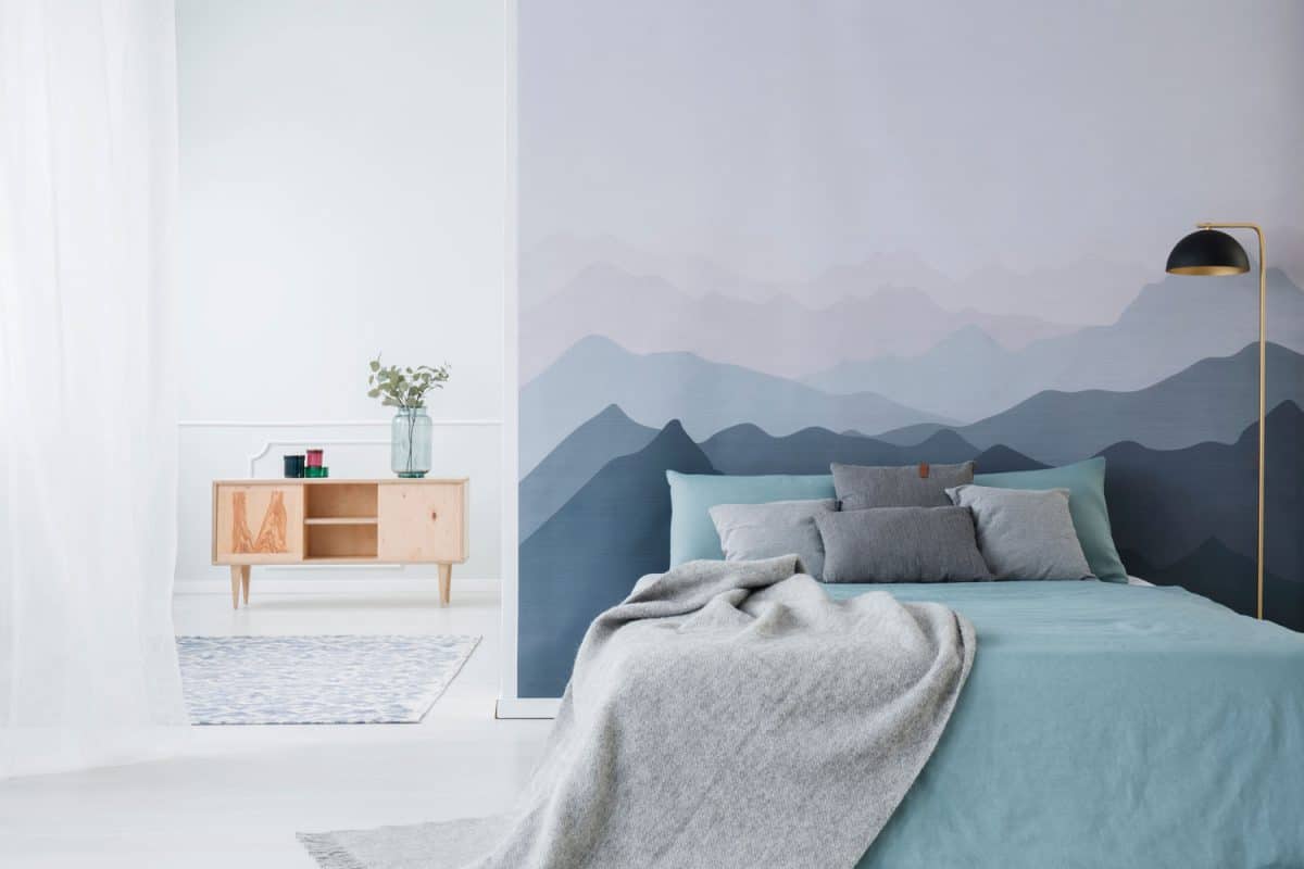 A cozy blue and white color combination bedroom with mountain paintings on the head board