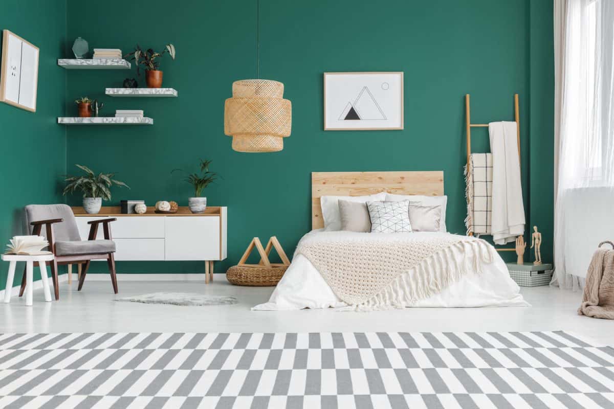 A green colored bedroom fused with white beddings, white wooden furniture's and white flooring
