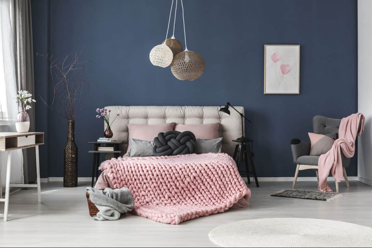 A huge dark blue wall paired with pink and beige beddings