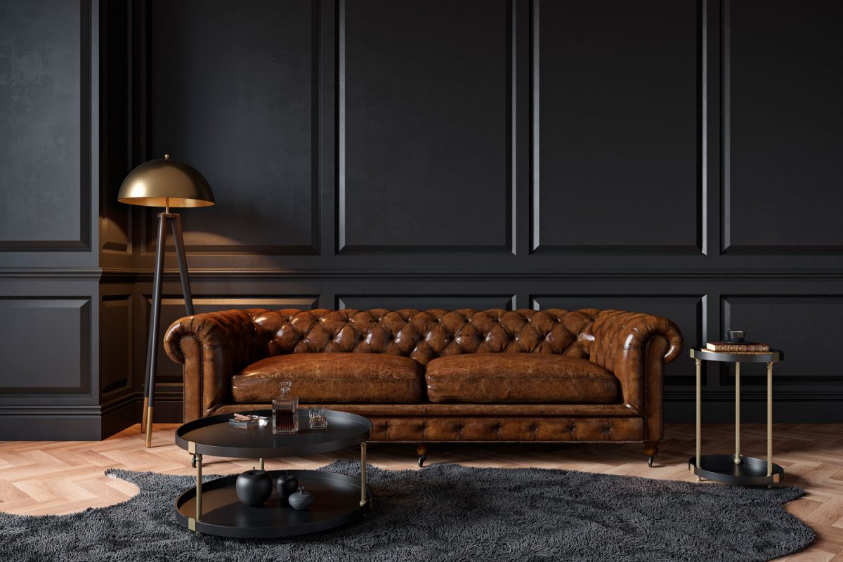 A leather sofa inside a black living area with black irregular rug