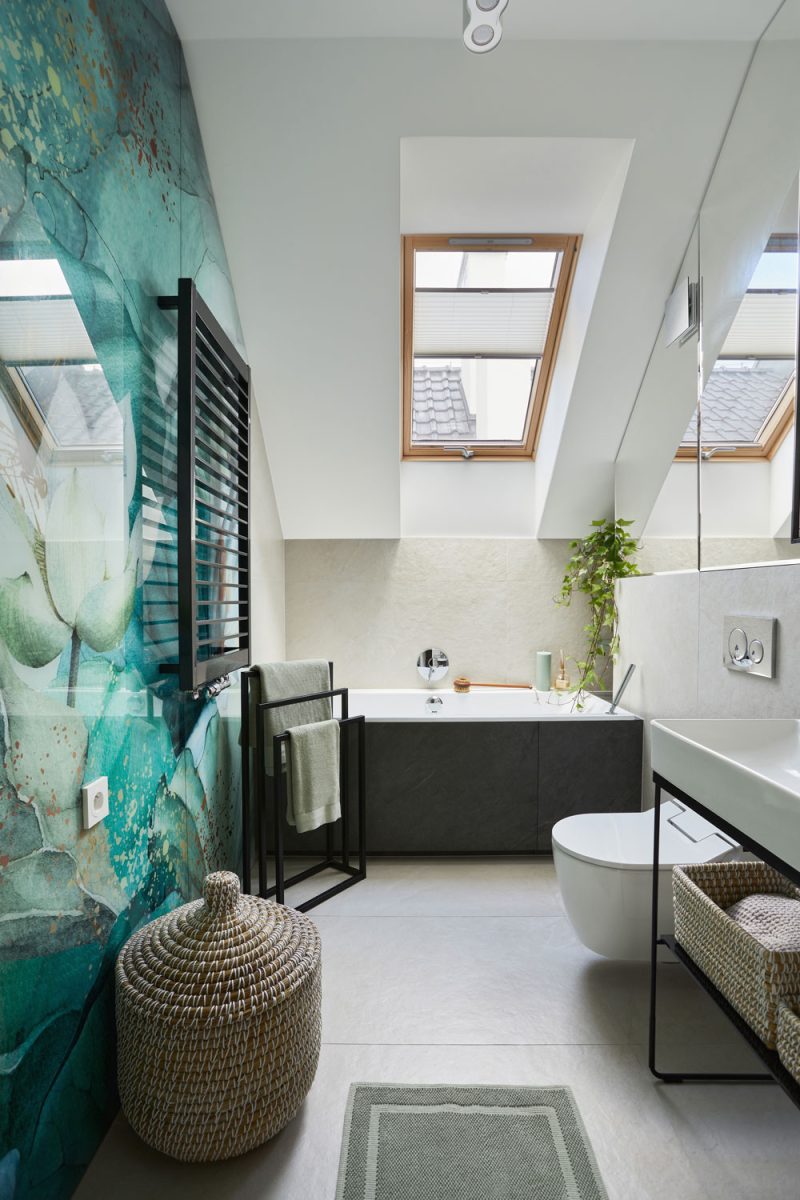 A mansard style narrow bathroom with white ceiling and green decorated wallpaper