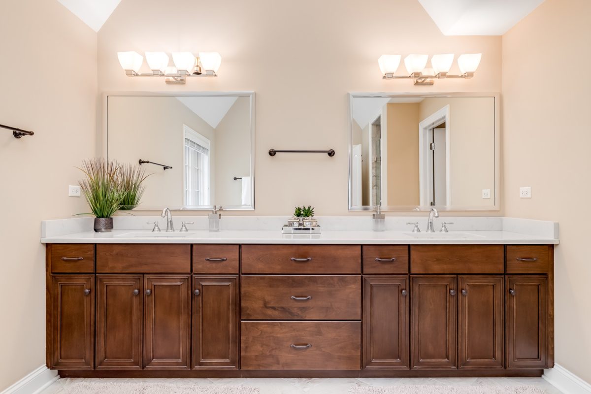 A modern master bathroom with a dark wood vanity and light colored counter top.